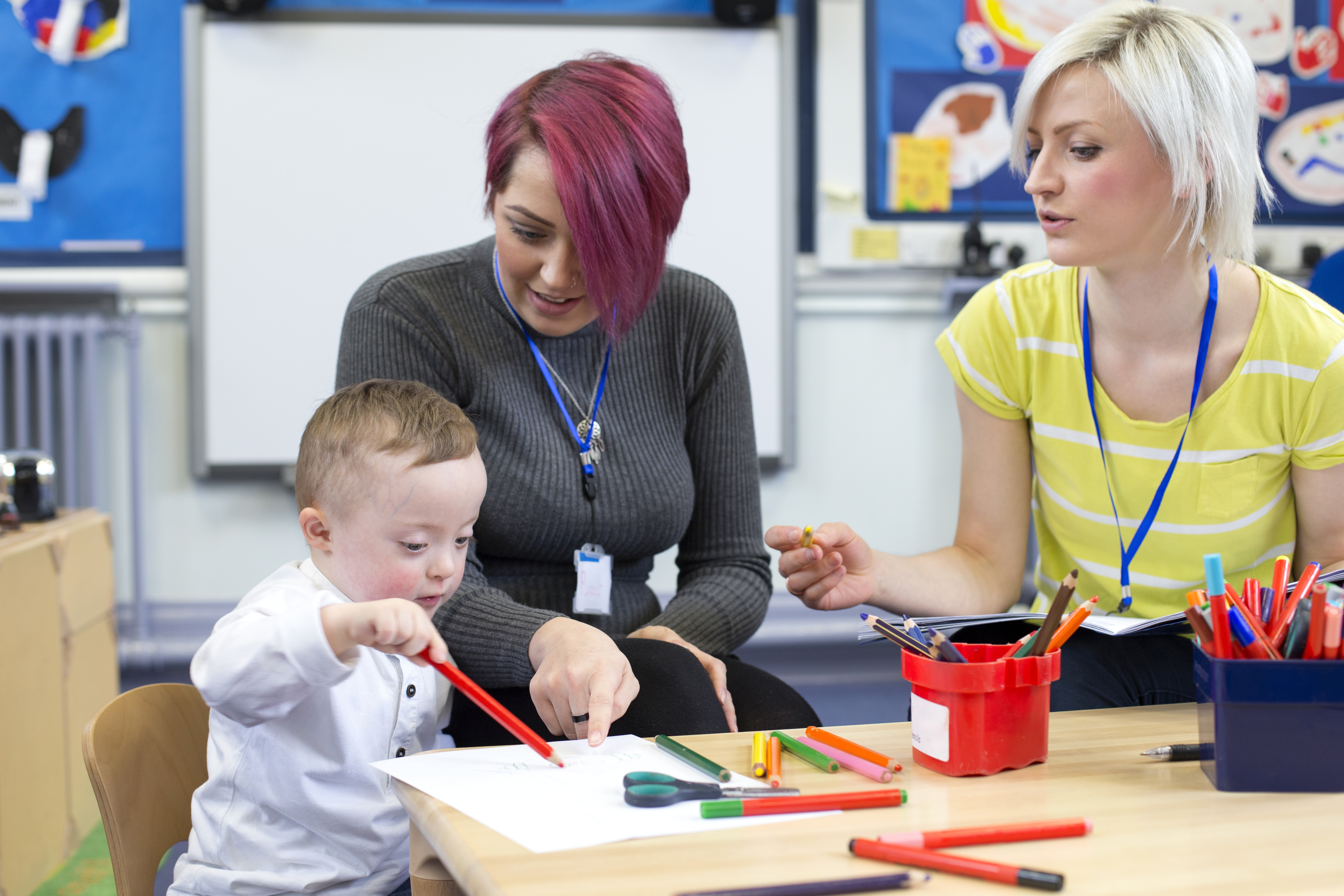 Teachers engaging with preschooler in writing activity